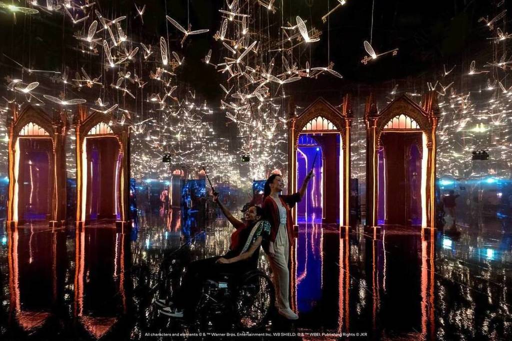 One of the many dazzling Harry Potter: Visions of Magic zones featuring winged keys flying around above two guests waving their wands.