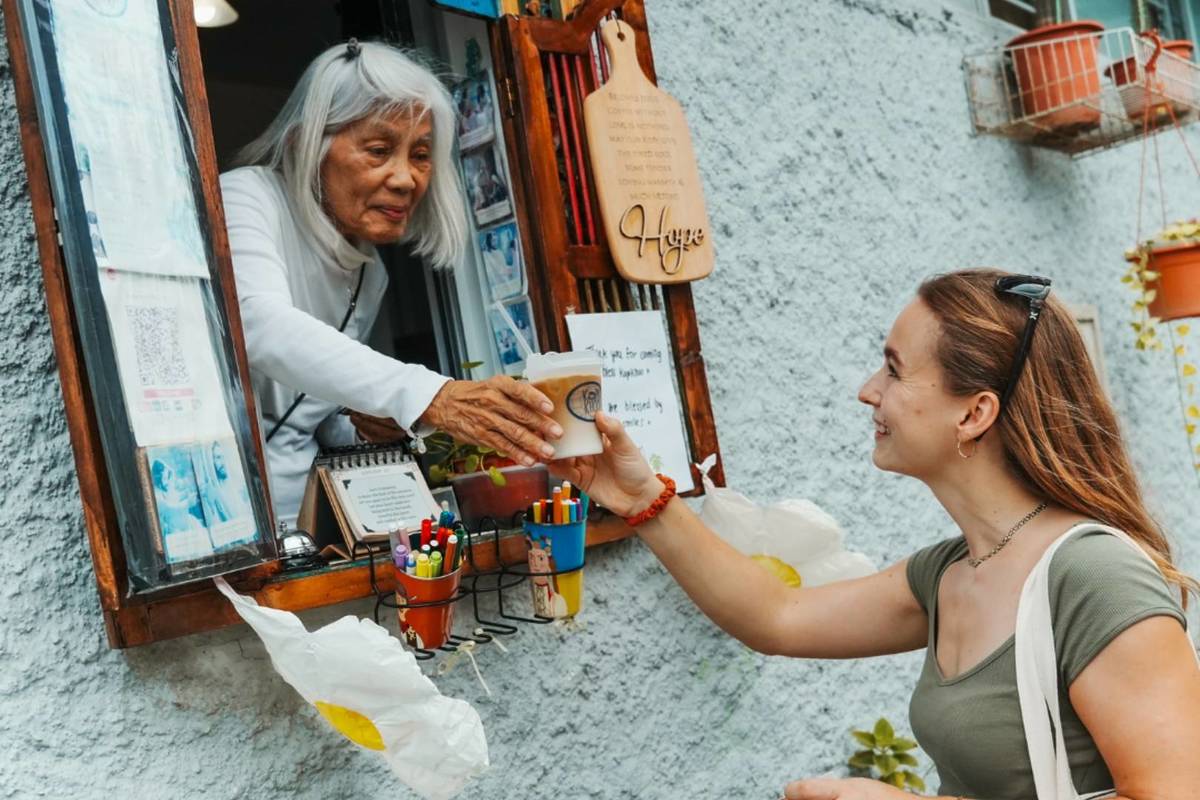 A woman receiving a beverage from a window vendor
