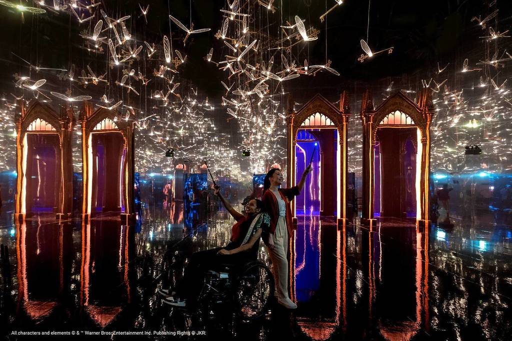 One of the many dazzling Harry Potter: Visions of Magic zones featuring winged keys flying around above two guests waving their wands.