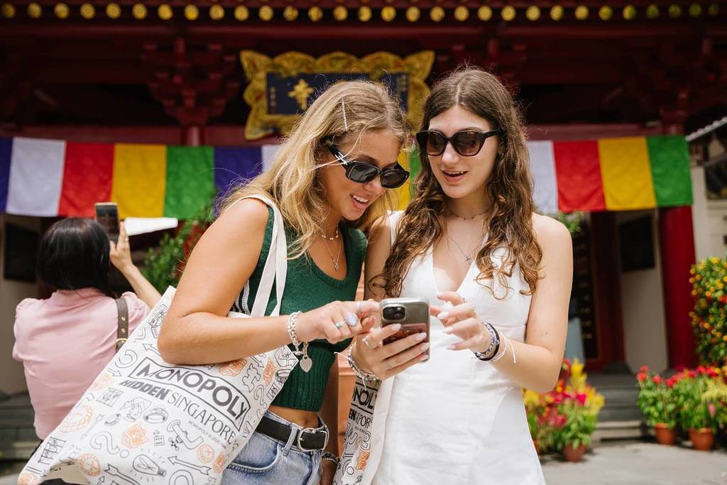 Two women navigating HIDDEN: MONOPOLY Singapore - Chinatown's puzzles sent to their phones