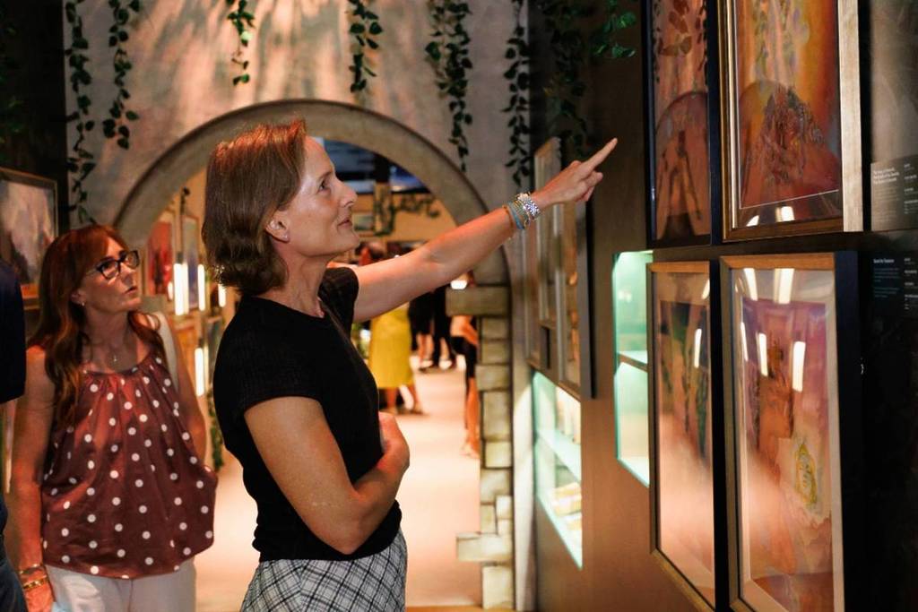 A woman pointing at a series of artworks displayed along the walls of Portals