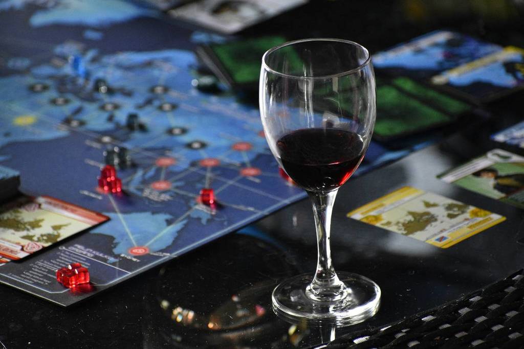 A glass of red wine next to a board game