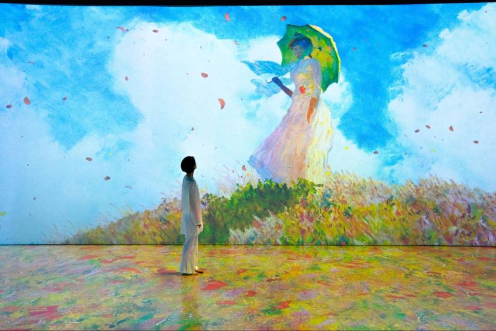 A woman stood admiring Claude Monet's "Woman with a Parasol" painting at GROUNDSEESAW's Monet Inside exhibition