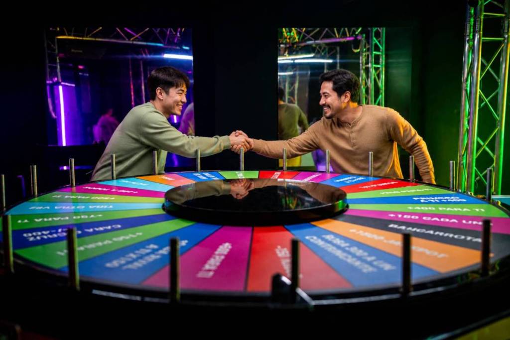 Two contestants shaking hands before spinning the giant Multiplier Wheel