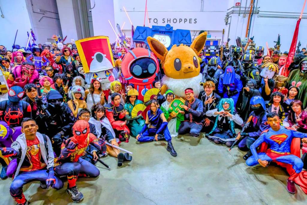 A group photograph featuring Singapore Comic Con guests cosplaying various characters from hit franchises such as Avatar: The Last Airbender, Helldivers, Fallout, Marvel, Masters of the Universe, DC, K-Pop Demon Hunters, Pokémon, and more