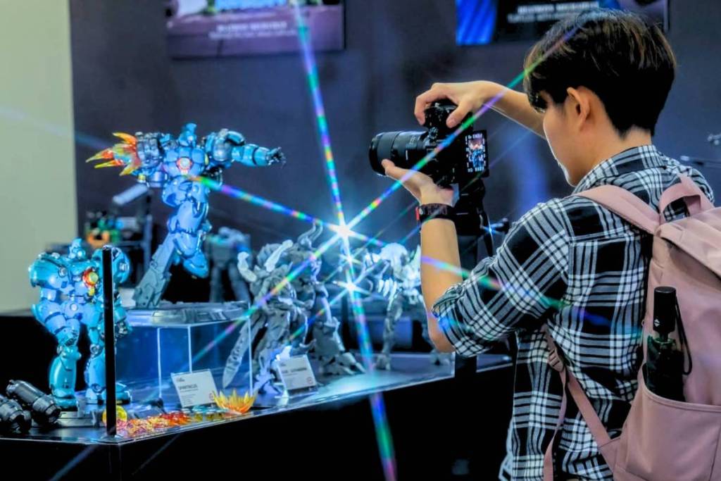 A collectible enthusiast photographing a series of collectable statues on display at Singapore Comic Con