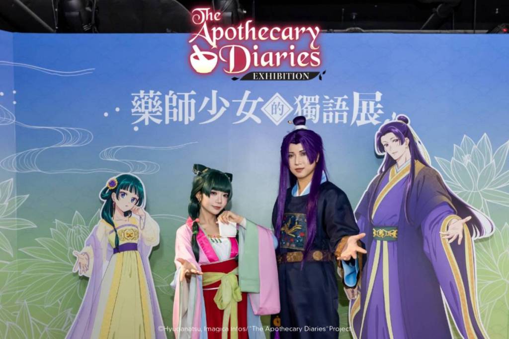 Cosplayers dressed as Maomao and Jinshi stood side-by-side with their animated counterparts