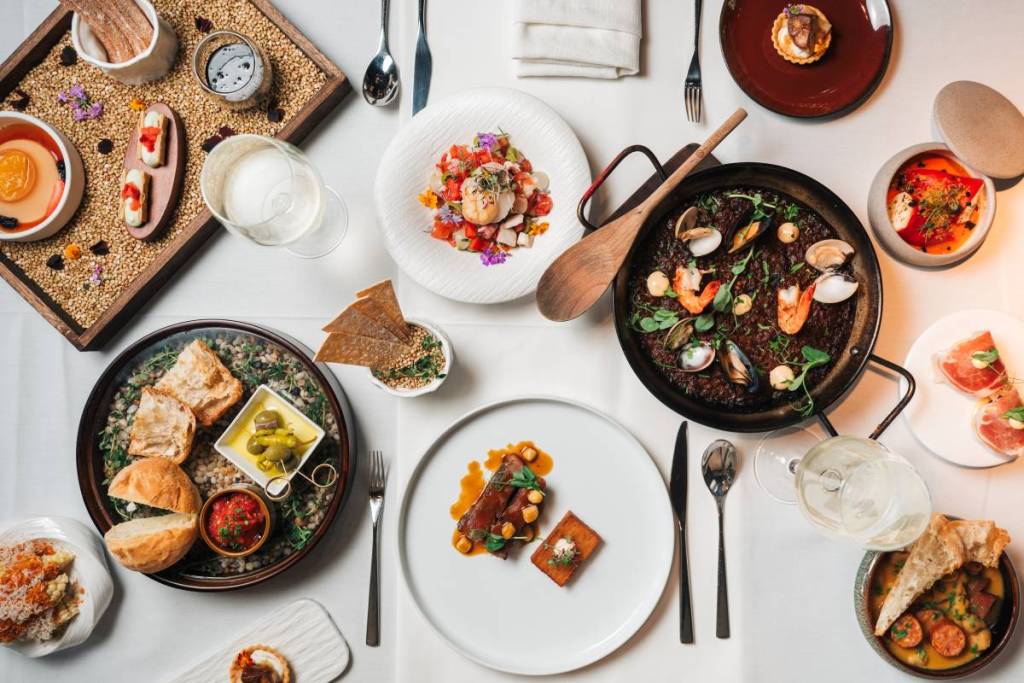 a flatlay of elevated spanish food from UNA at the Alkaff Mansion on a white tablecloth