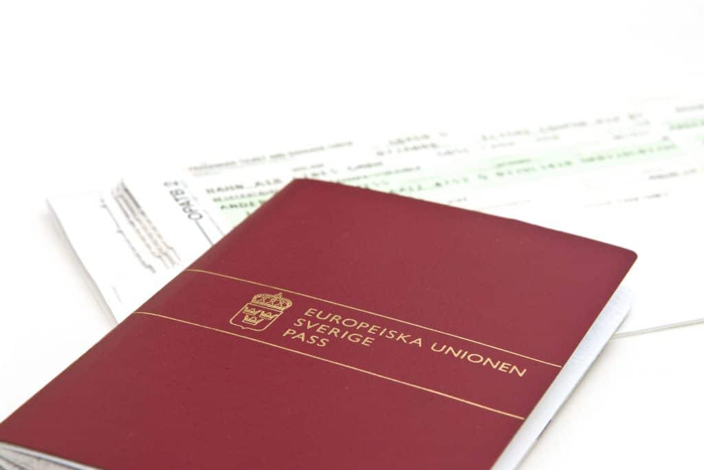 A Swedish passport on top of a plane ticket.