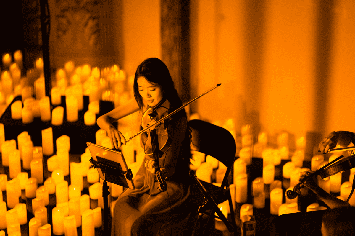 A violinist performing on stage surrounded by candles at a Candlelight concert