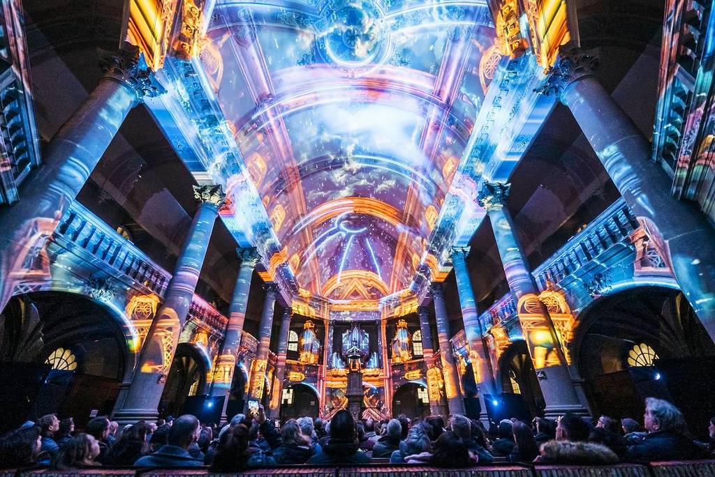 the interior of a grand historic venue is illuminated with cosmic projections at Genesis light show