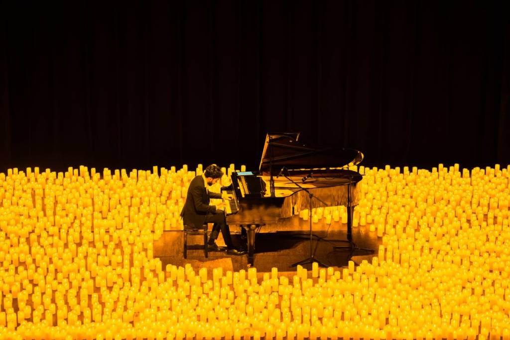 Klavierspieler spielt bei einem Candlelight-Konzert auf einem Flügel, umgeben von etlichen Kerzen