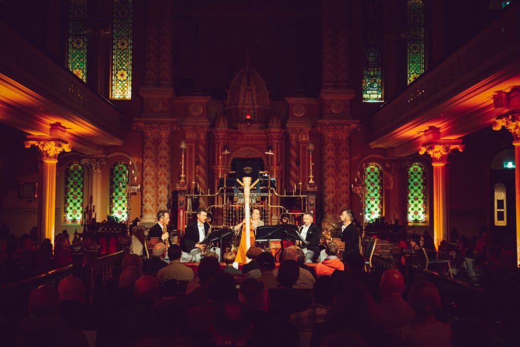 musicians performing instruments at fair end of the concert hall in low light