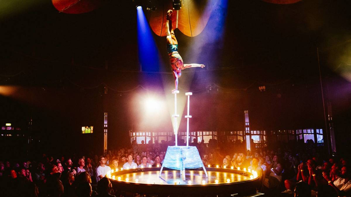 A performer does a one-arm handstand on a pole high above the stage at La Ronde.