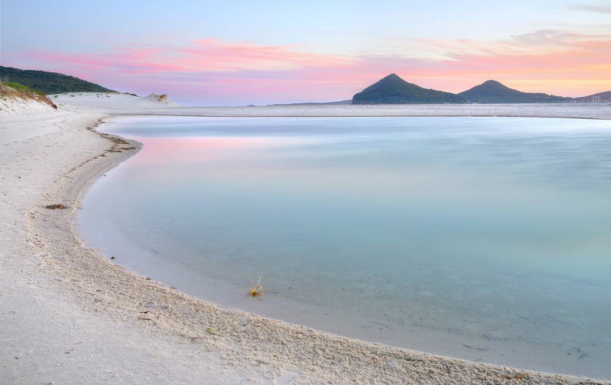 Jimmys Beach, with the Winda Woppa Lagoon in the background, as the sun rises over the ocean.