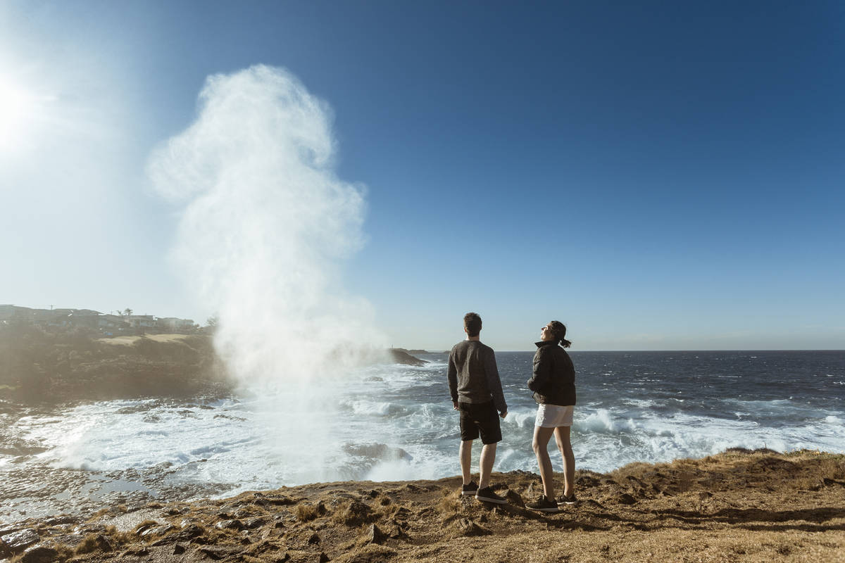 Couple watching the water plume from the Kiama blowhole, one of the most unusual day trips from Sydney to take.