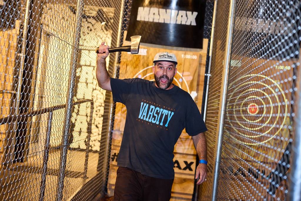 A bearded man in a cap holds an axe at MANIAX axe throwing in Sydney's Inner West.
