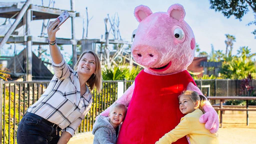 A woman takes a selfie of herself, Peppa Pig, and two children.