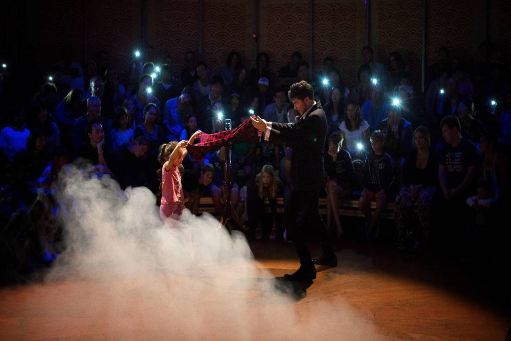 A magician performing a trick with a young girl at Sydney Spiegeltent