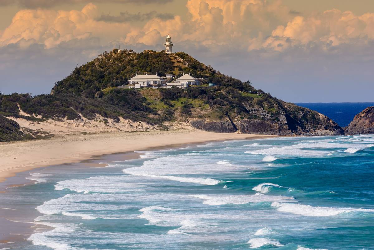 Large swell rolling onto the beach at Seal Rocks, with the historic lighthouse in the distance