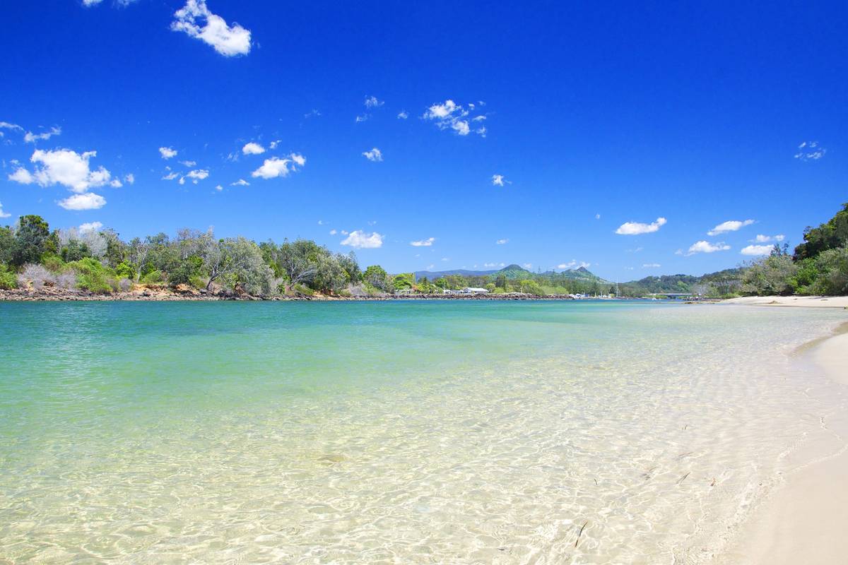 A beach in Brunswick Heads on a sunny day with blue skies and crystal clear blue waters
