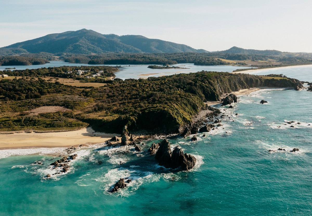Wallaga Lake on the Sapphire Coast, framed by lush green hills and emerald waters, with expansive open views across the landscape - part of the Great South Coast Walk in NSW