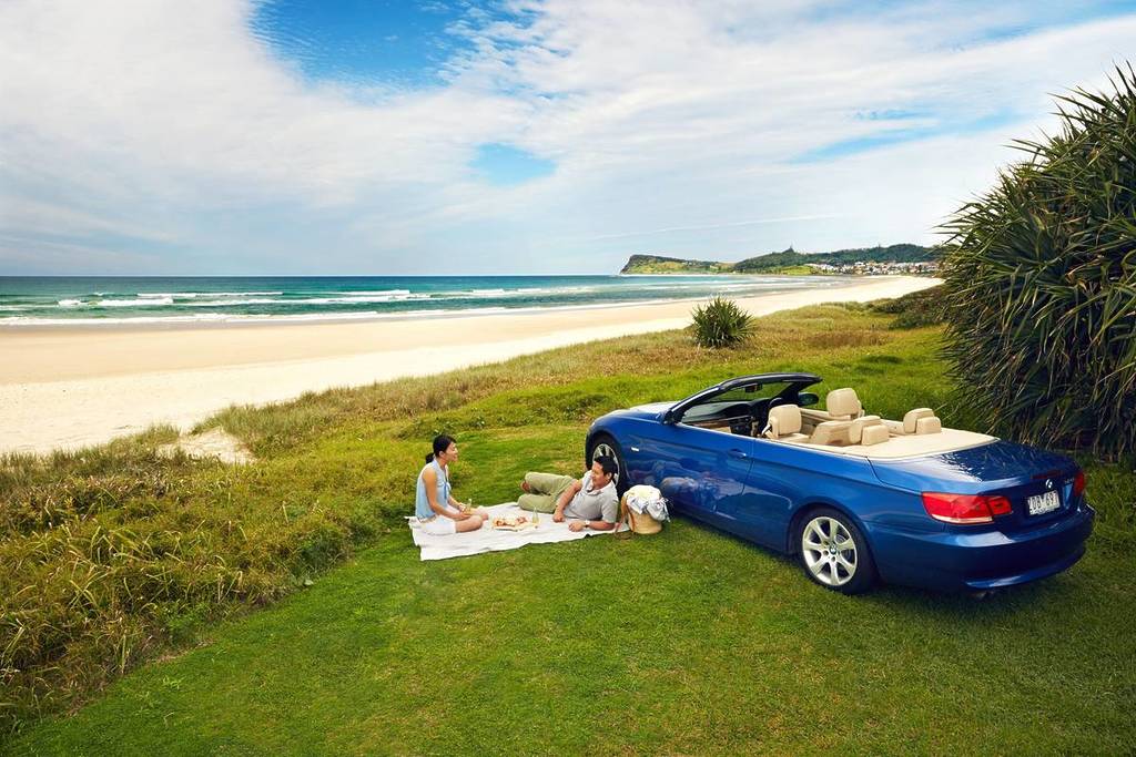 Two people having a picnic on an empty beach in Lennox Head, with turquoise waters and a clear sunny sky overhead