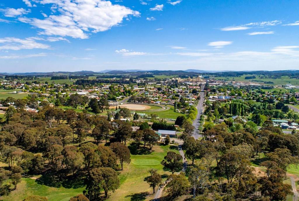 Aerial view of Oberon, NSW, showing the town surrounded by lush forests and rolling countryside in winter