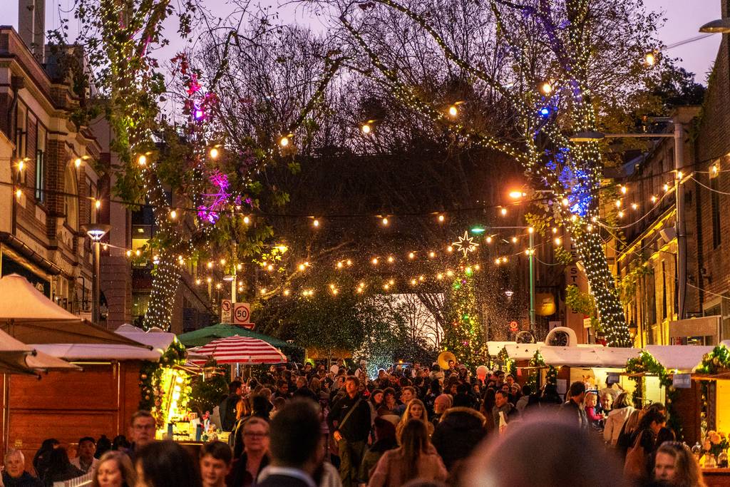 Festive street market with fairy lights, snow and crowds at Christmas in July in The Rocks