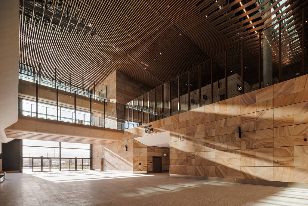 Sunlit sandstone arrivals hall at Western Sydney Airport with “Welcome to Sydney” signage