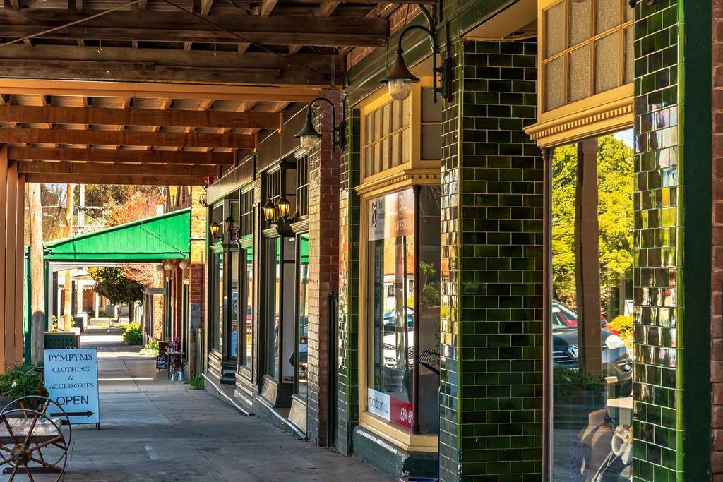 Covered walkway with heritage shopfronts in Millthorpe, NSW, showcasing vintage green tiles and warm lighting