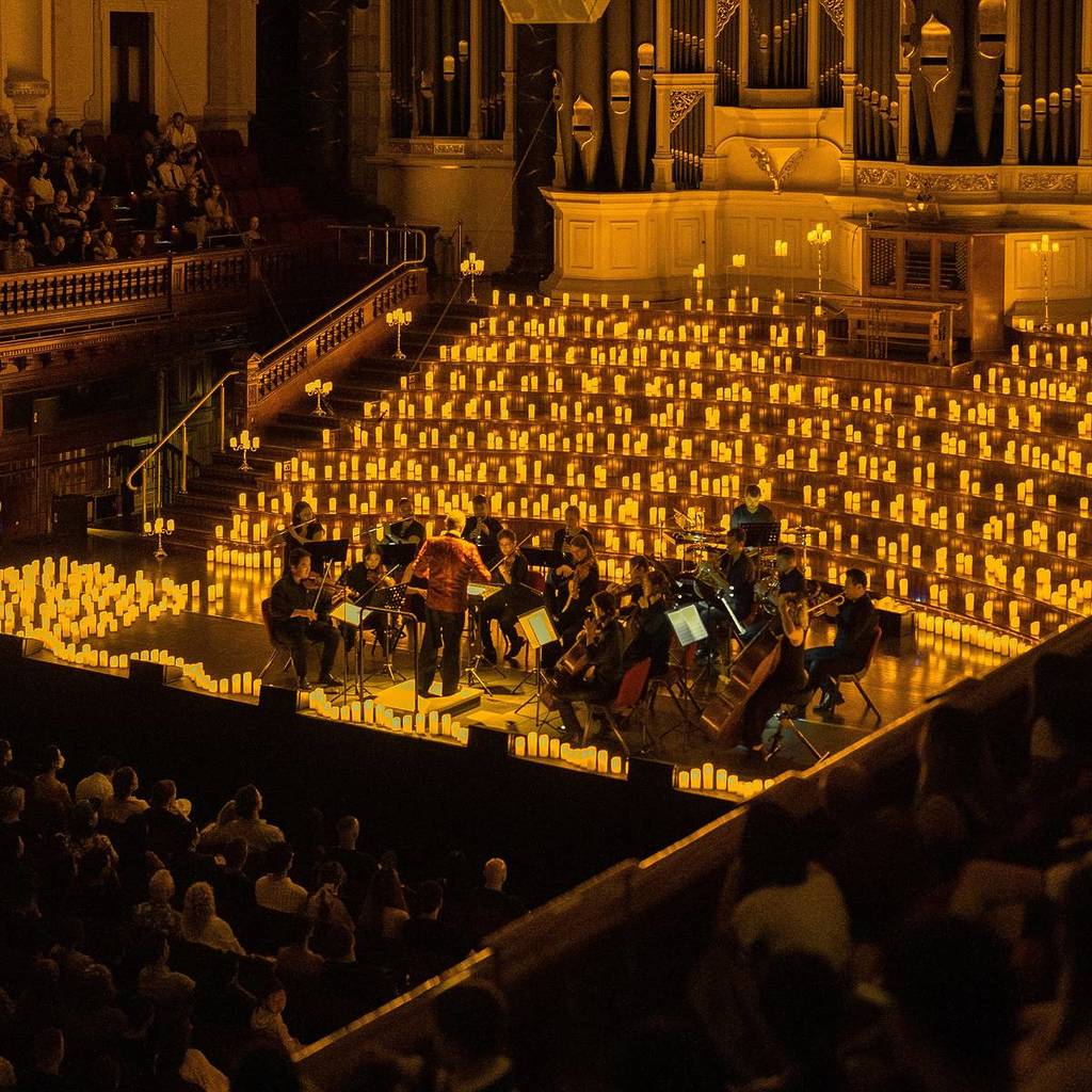 Sydney Town Hall, illuminated with golden lights as an orchestra plays.
