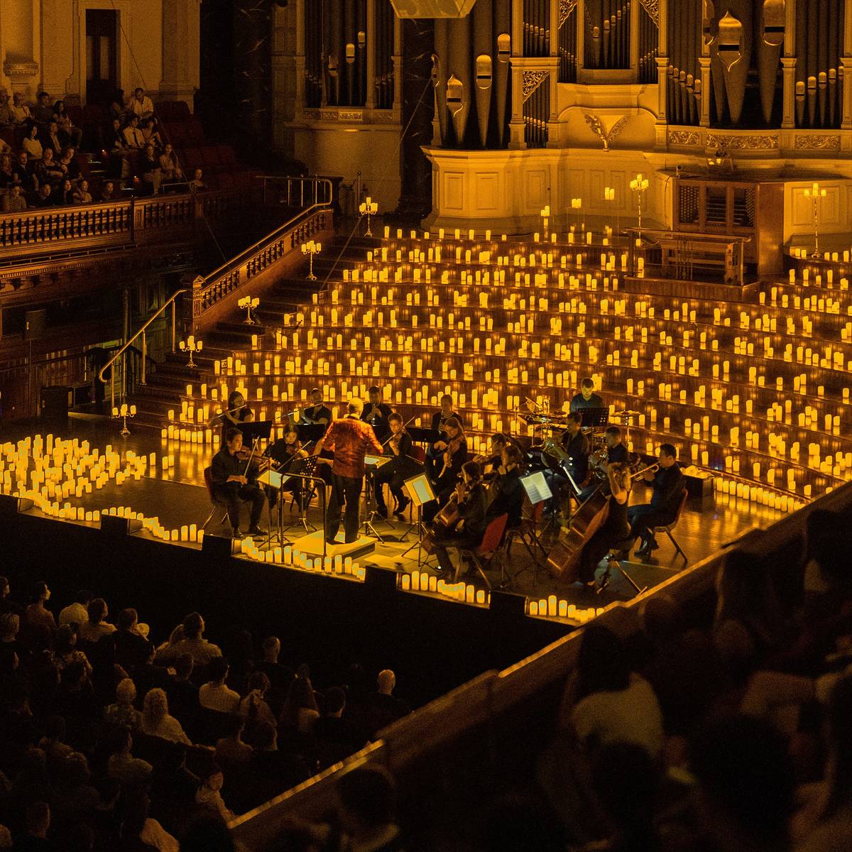 Sydney Town Hall, illuminated with golden lights as an orchestra plays.