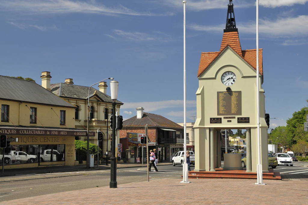 Heritage buildings and the war memorial clock tower in the centre of Mittagong, with antique shops, old facades and locals crossing the main street