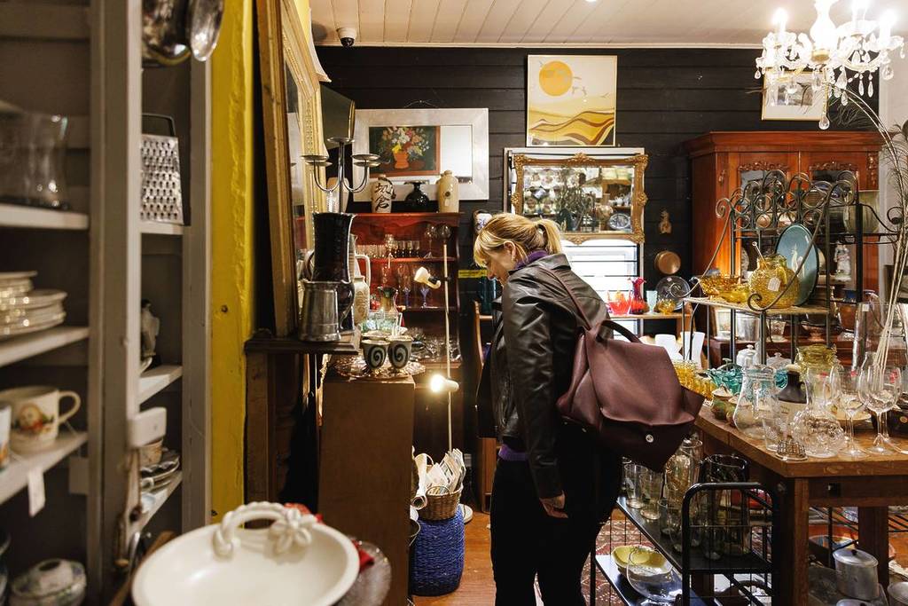 A woman browsing antique items in a quaint vintage store in Mount Victoria, Blue Mountains, showcasing an assortment of retro goods and curios