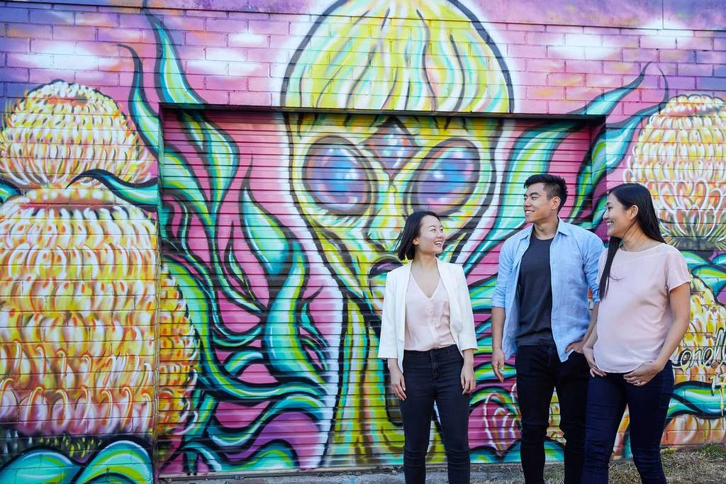 Three friends walking past colourful mural art on the Street Art Walk in Katoomba, Blue Mountains