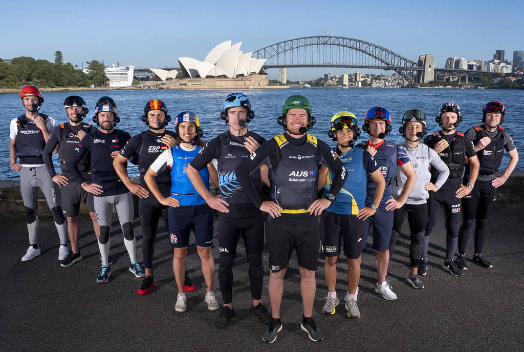 The SailGP crew stand in a line, posing for a photo with the Harbour Bridge in the background.