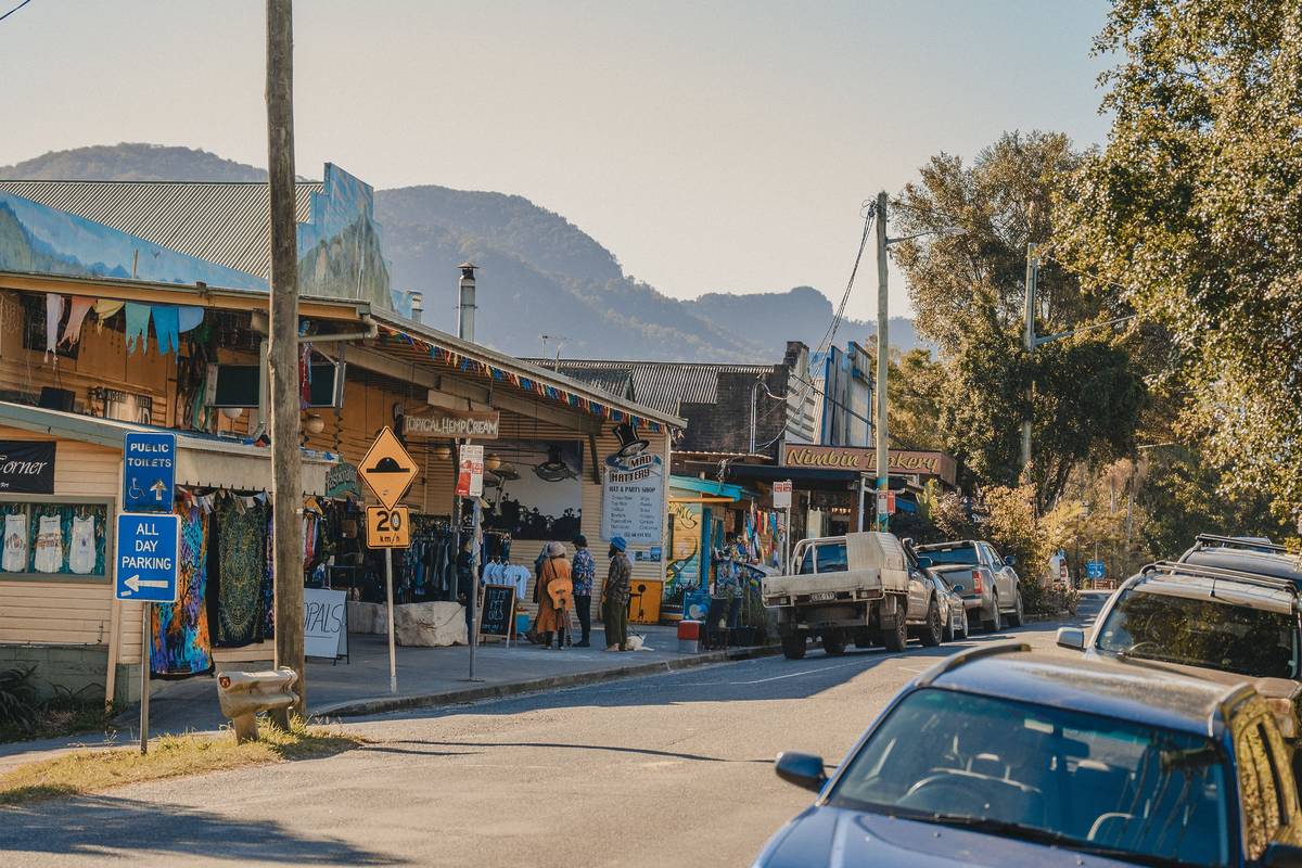 Street view of Nimbin, showcasing colorful storefronts, with mountains in the background