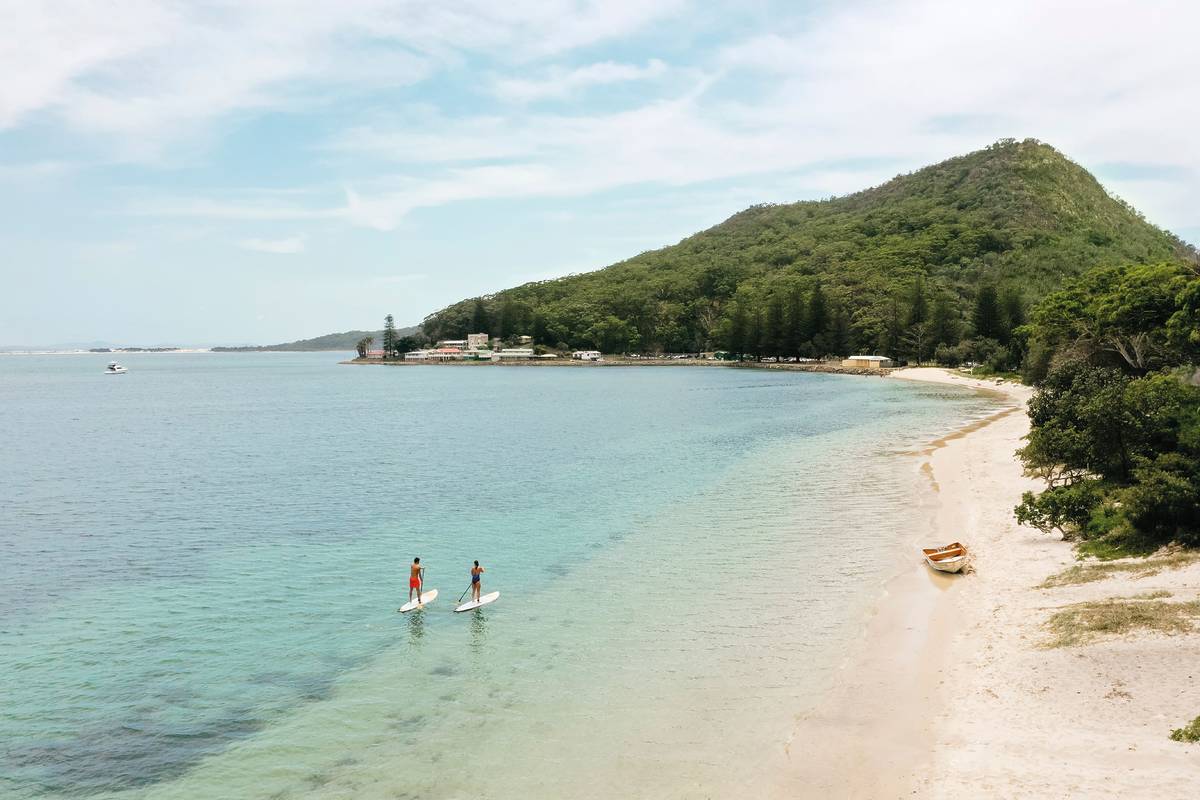Two people paddleboarding in the clear turquoise waters of Port Stephens
