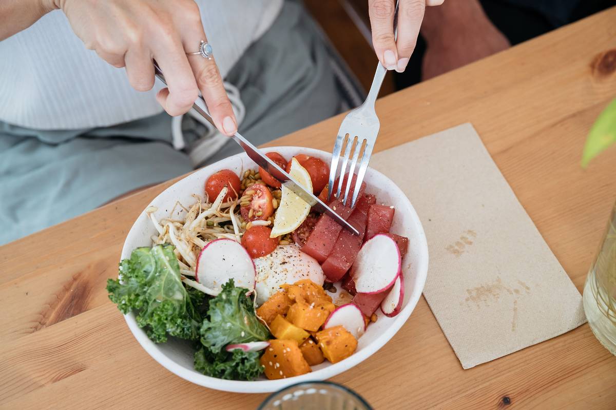 Close-up of a fresh and healthy meal with tomatoes, kale, radishes, and pumpkin on a wooden table at a cafe in Central Coast