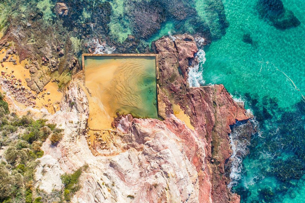 Aerial view of Aslings Beach Rock Pool in Eden, framed by pink cliffs and turquoise water