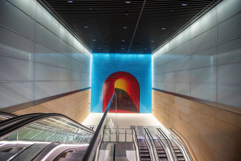 Bright blue and red tiled mural at the end of an escalator at Gadigal Station, named among the World's Most Beautiful Passenger Stations for 2025
