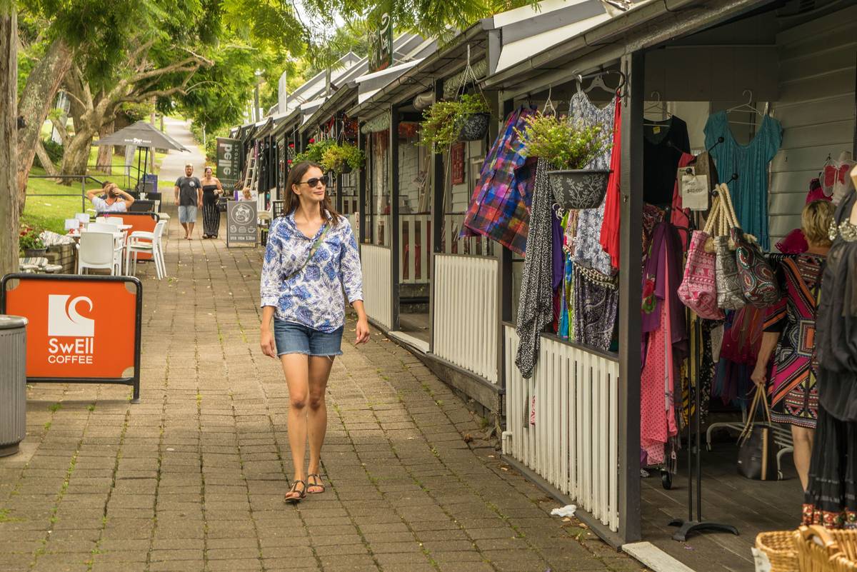Woman walking past colourful stores on Collins Street in Kiama's town centre