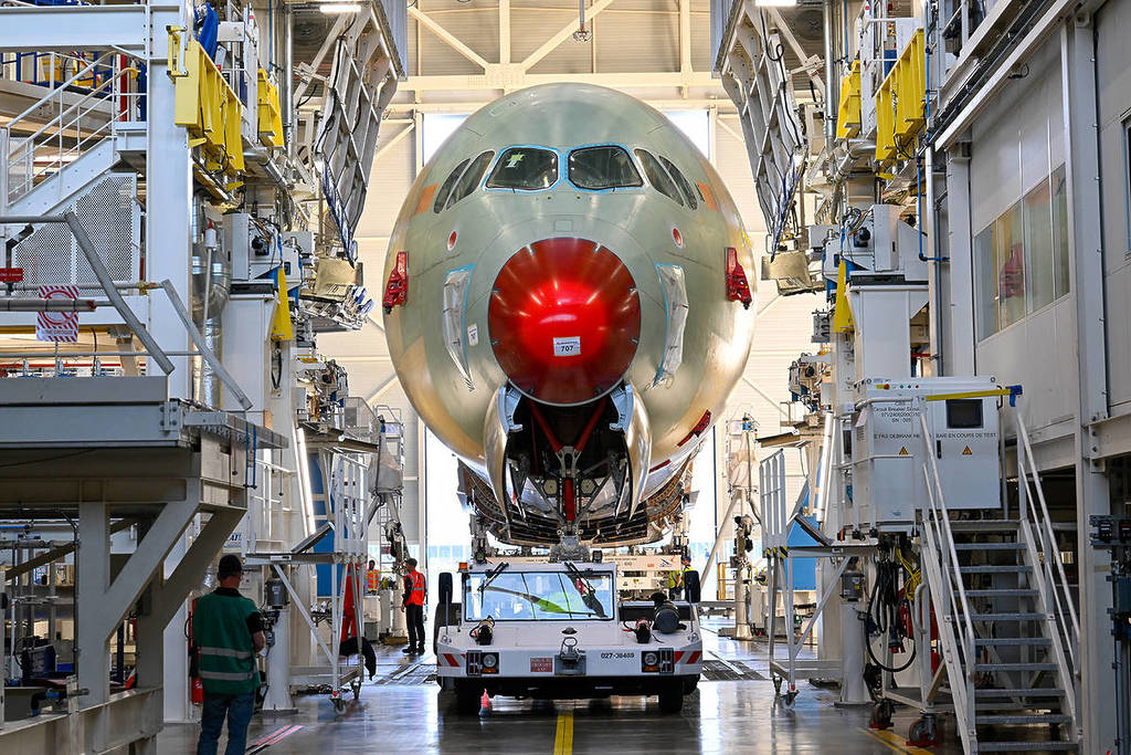 Qantas' Airbus A350-1000ULR on the tarmac, with its nose section visible and a close-up of the aircraft’s red nose cone under assembly