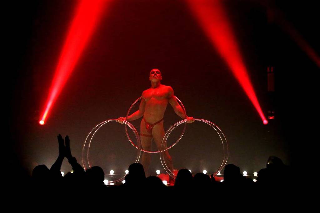 A man stands on stage at La Ronde holding a set of silver hula hoops.