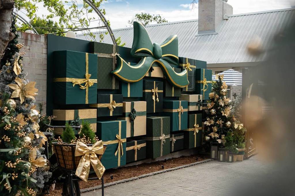A large wall of oversized green and gold Christmas presents topped with a huge decorative bow at Camden Valley Inn