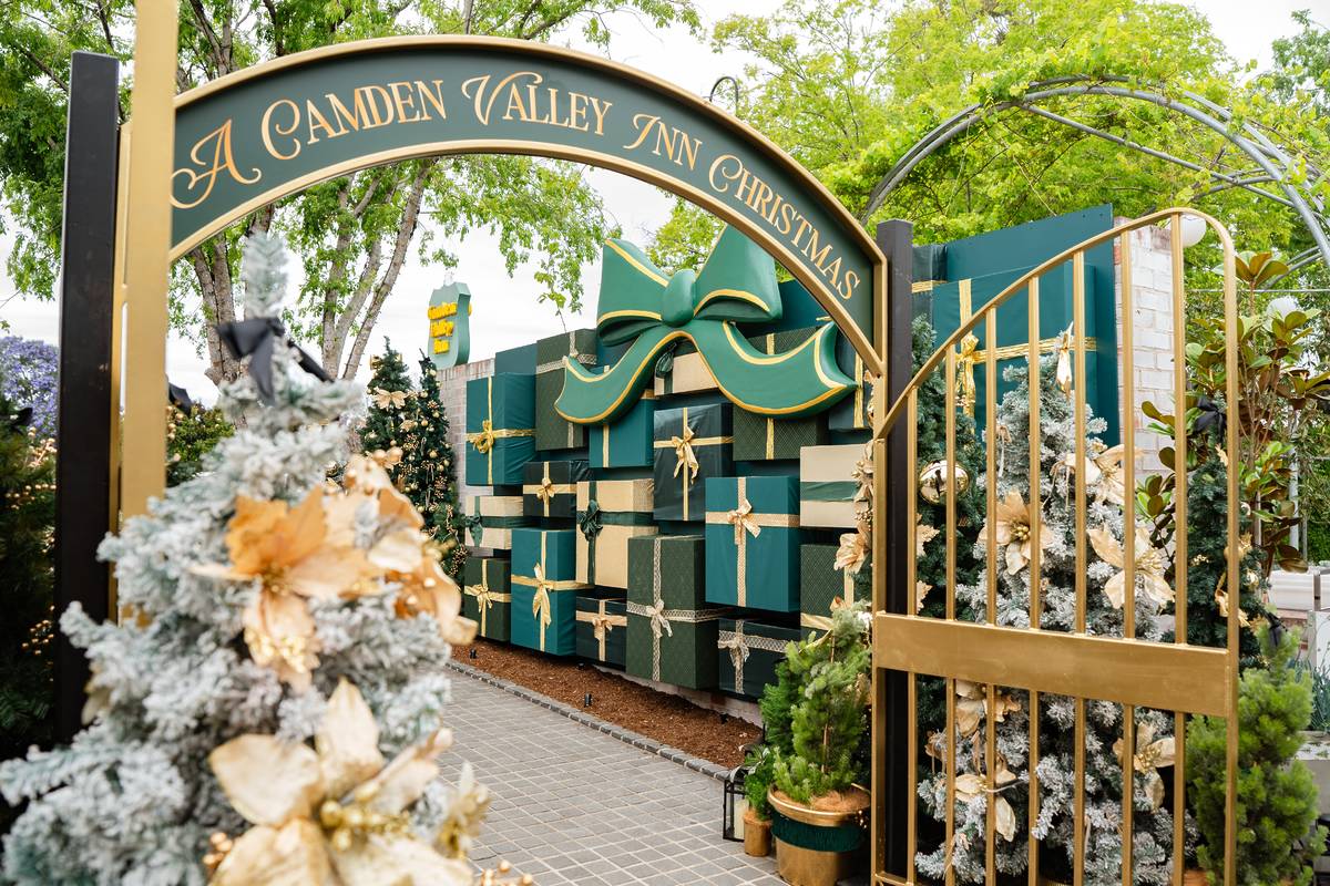 The “A Camden Valley Inn Christmas” archway leading to a walkway lined with decorated trees and a large wall of green and gold gift boxes