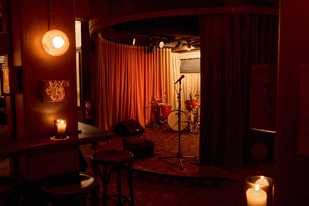 A dimly lit stage at Curtains Jazz Club with a microphone, drum kit and draped curtains creating an intimate performance space