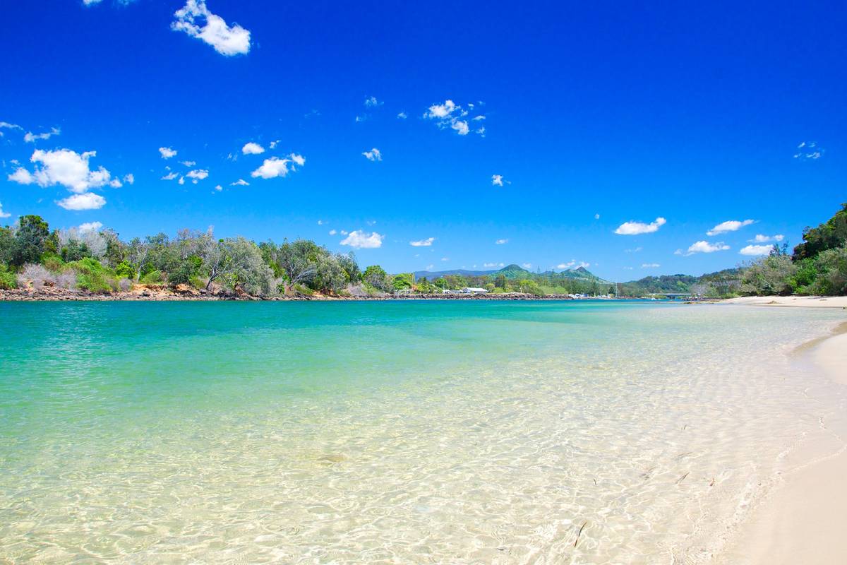 Clear shallow water and sandy shoreline at a calm river entrance in brunswick heads on a sunny day