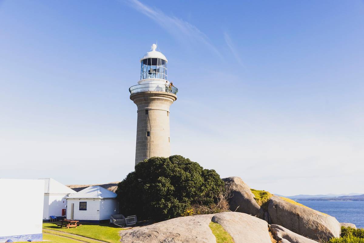 Montague Island lighthouse perched on rocky coastline, overlooking the ocean off Narooma